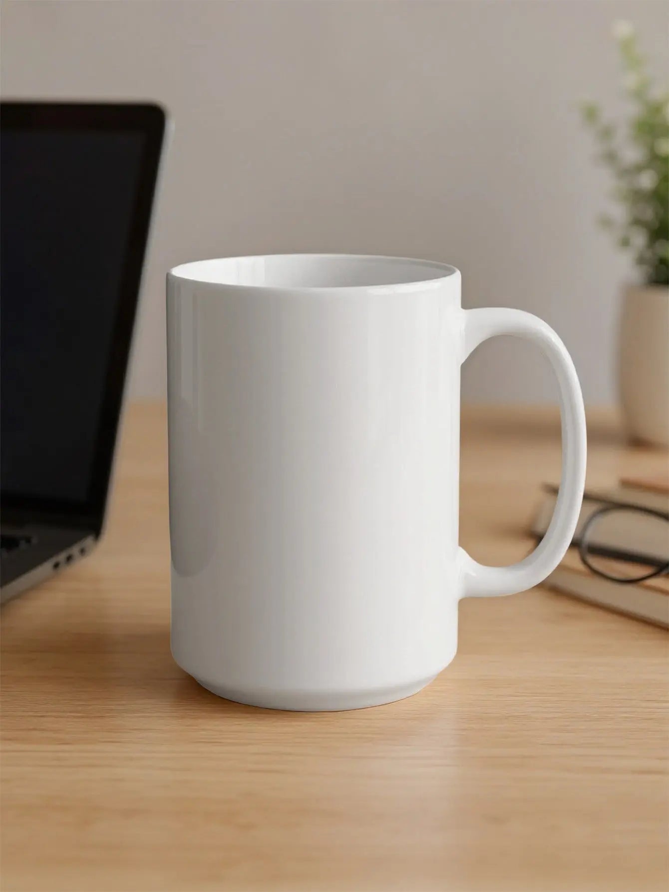 White ceramic mug on a wooden desk next to a laptop and glasses.