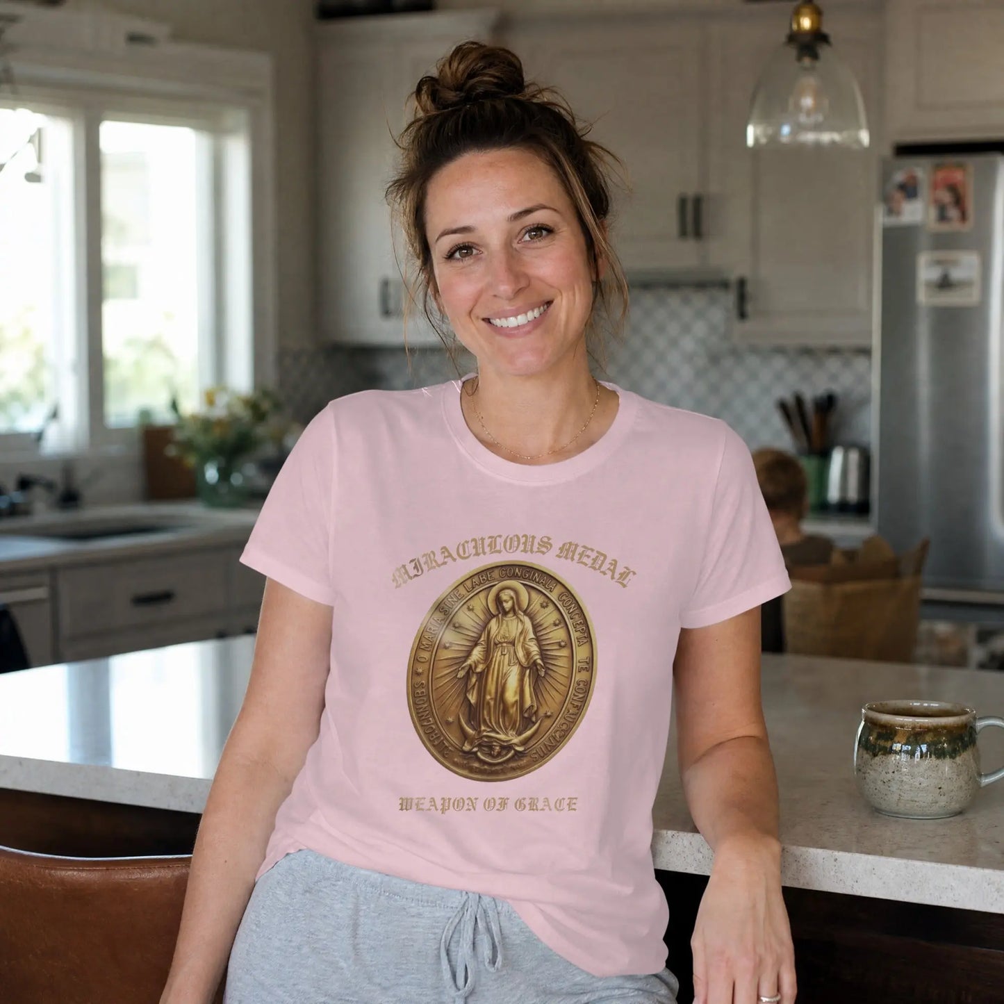 Pink t-shirt with a Miraculous Medal graphic and "WEAPON OF GRACE" text.