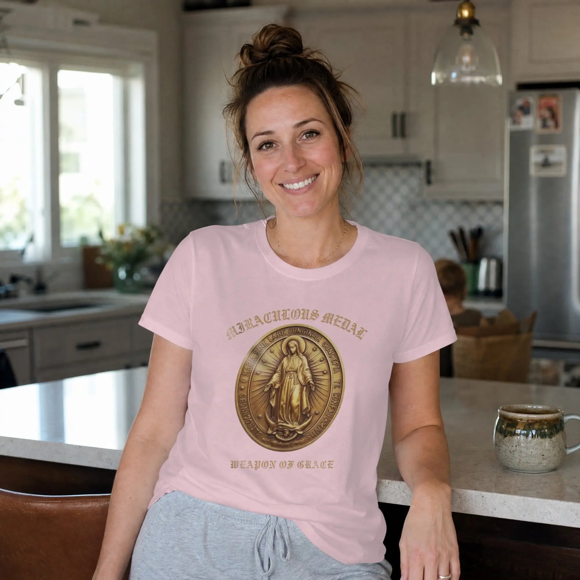 Pink t-shirt with a Miraculous Medal graphic and "WEAPON OF GRACE" text.