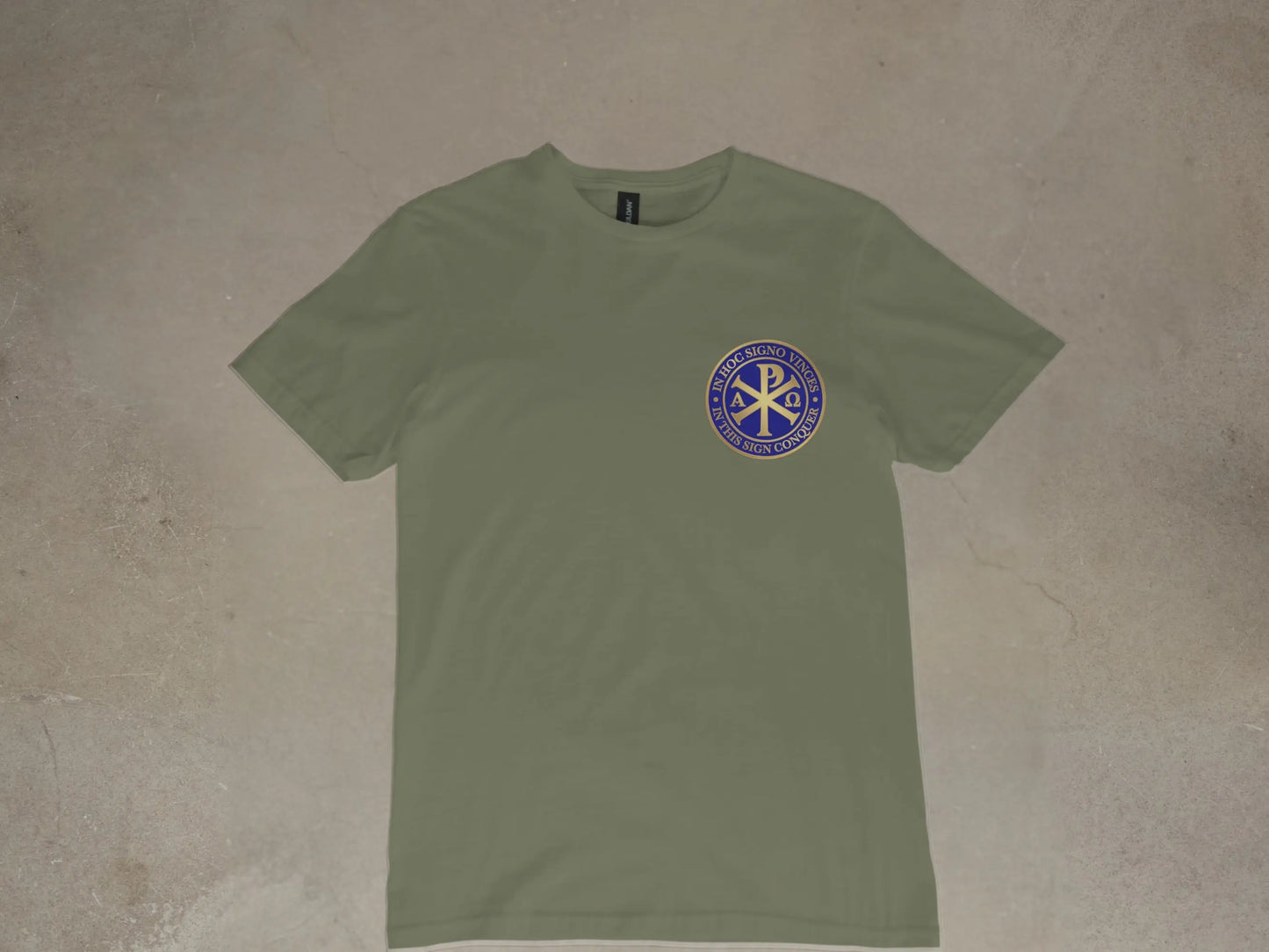 Olive green t-shirt with blue circular emblem featuring Chi Rho and text.