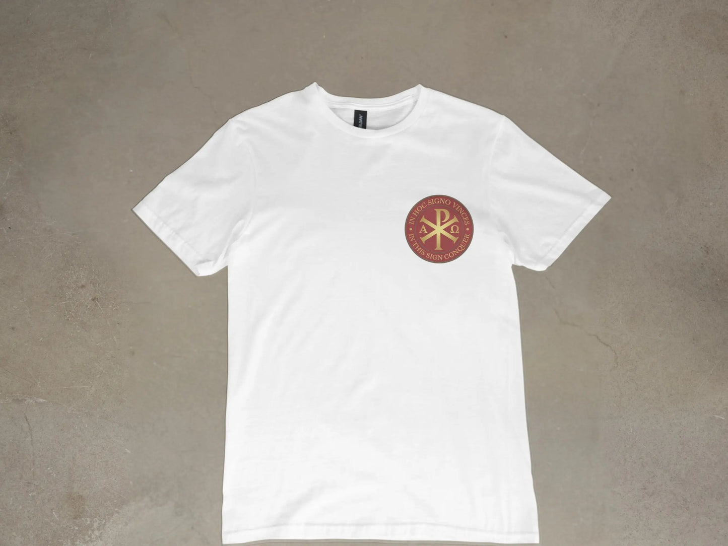 White t-shirt with a circular emblem featuring the Chi Rho symbol and Latin text "In hoc signo vinces."