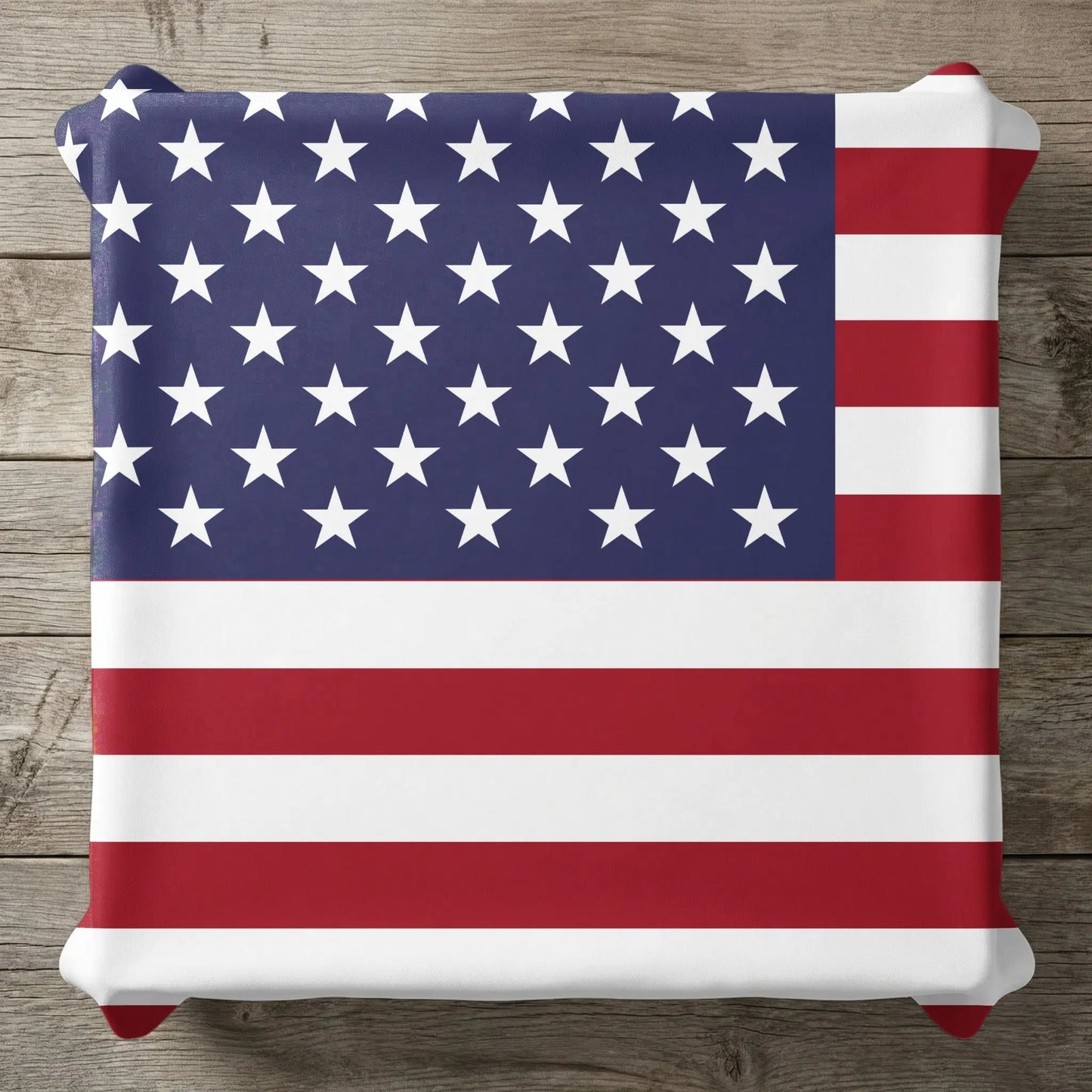 Pillow with American flag design on a wooden surface.
