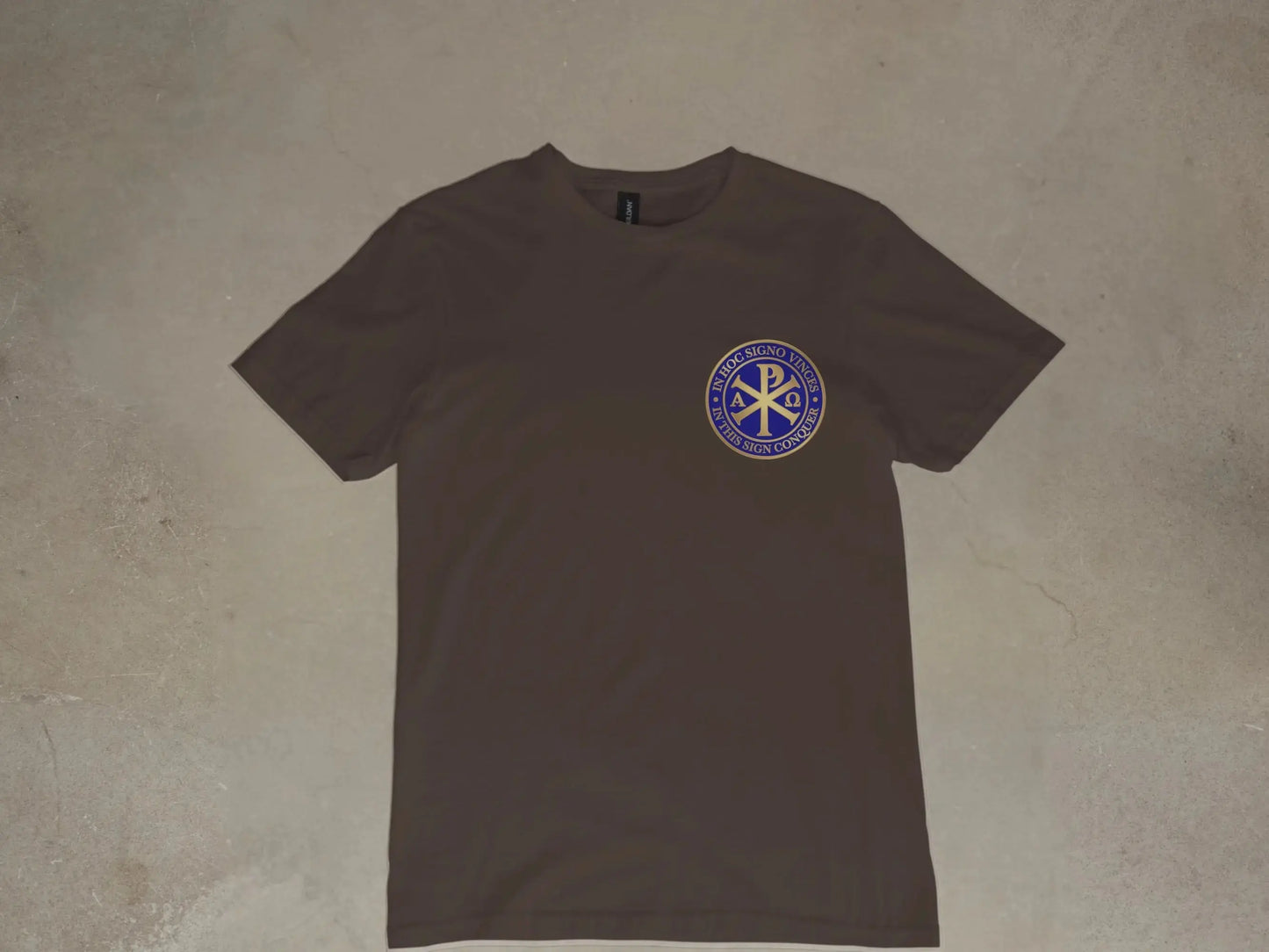 Brown t-shirt with a circular blue and gold logo featuring the Chi Rho symbol and Latin text.