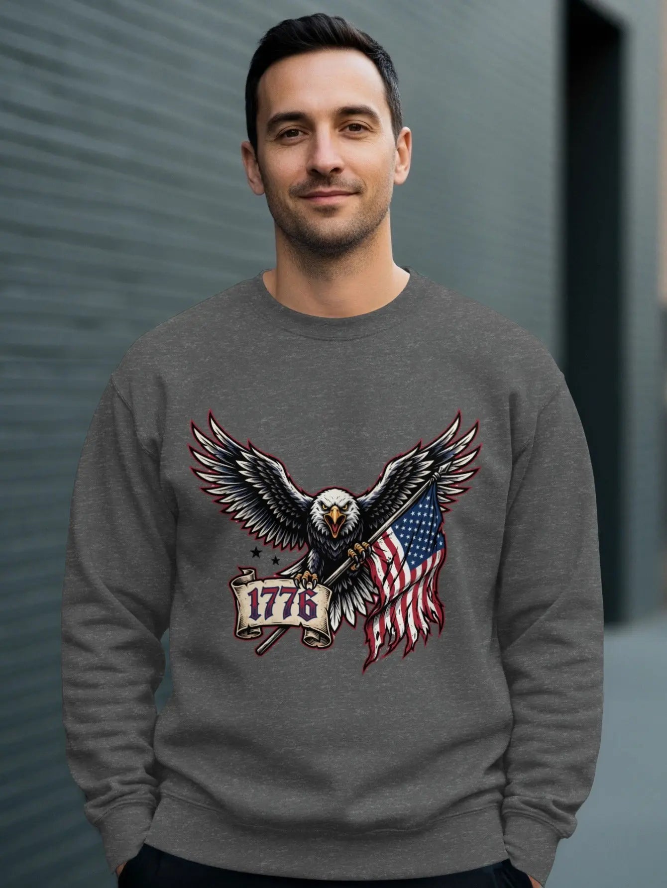 Eagle holding American flag and banner with "1776" on grey sweatshirt.