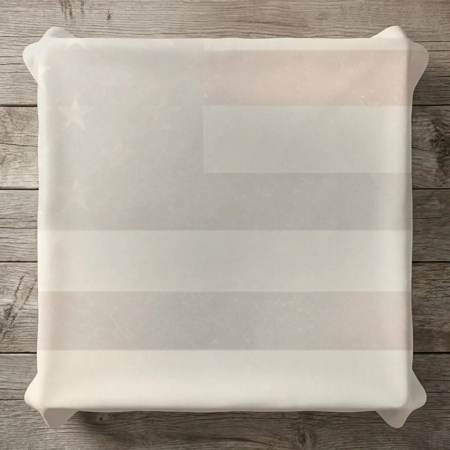 White fabric draped over a faded American flag pattern on a wooden surface.