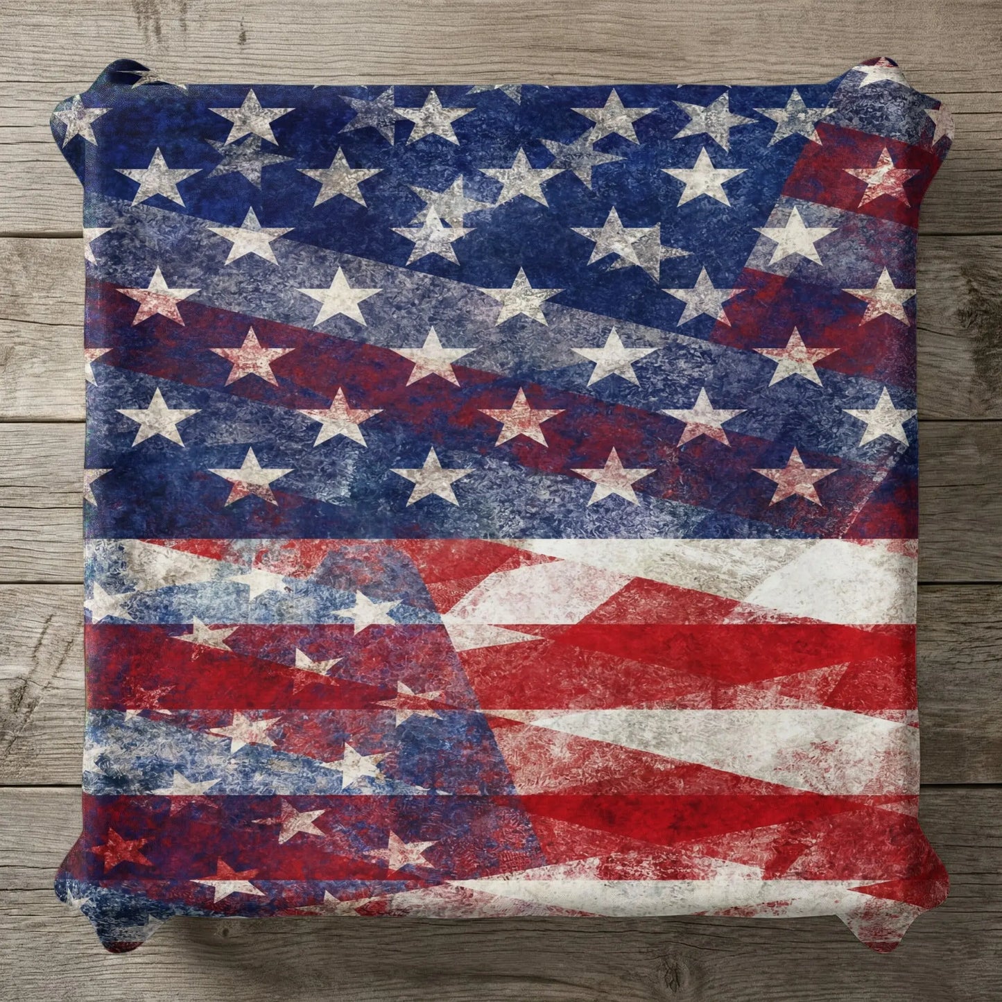 Distressed American flag pattern on a pillow against a wooden background.