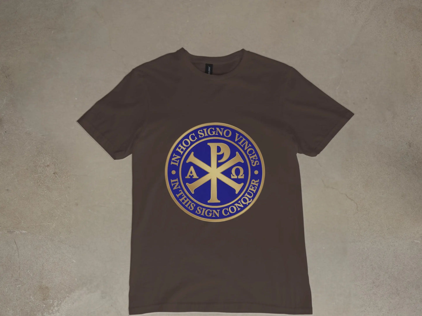 Brown t-shirt with circular gold and blue Chi Rho symbol and Latin text.
