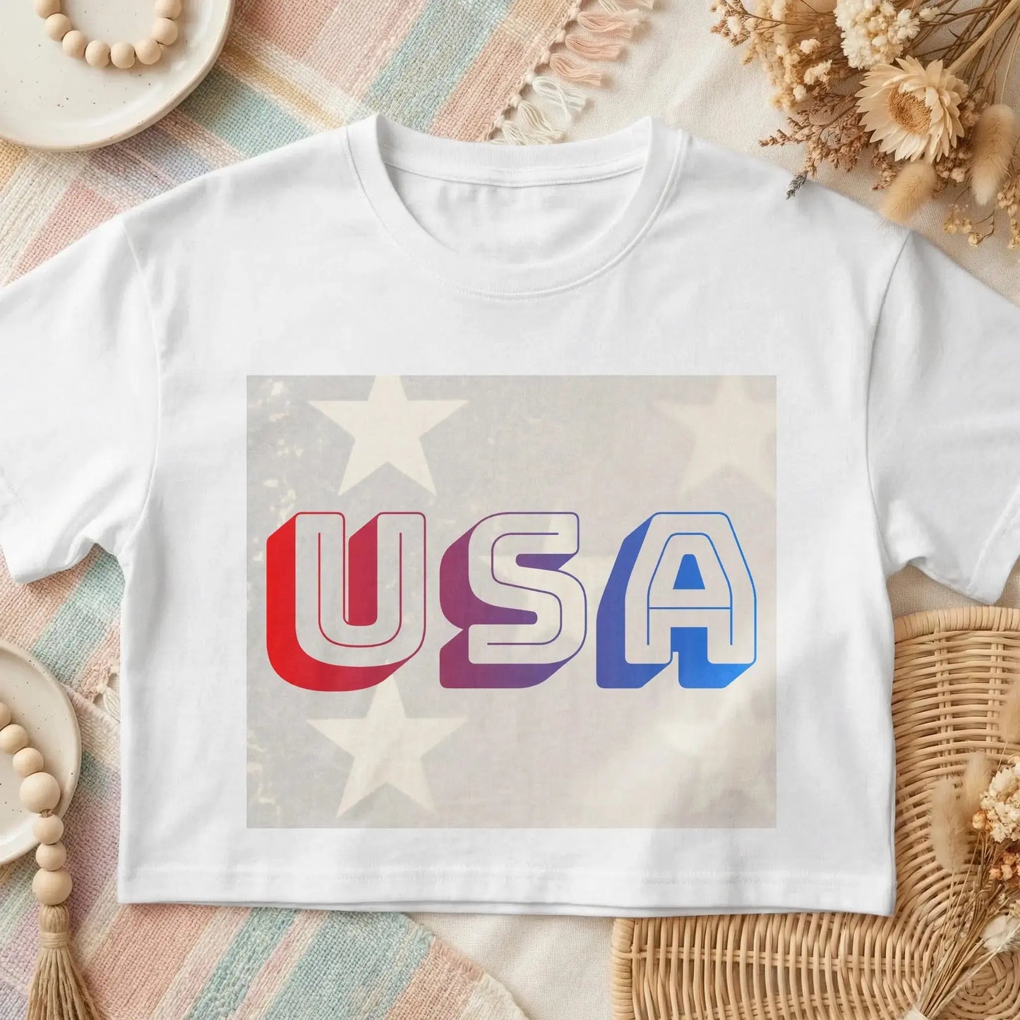 White t-shirt with 3D red, purple, and blue "USA" text on an American flag background.